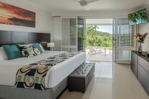A bedroom with a bed, a bench, a TV, and a view of the outdoors.