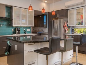 Eine moderne Küche mit einer zentralen Kochinsel, Barhocker und einem eingebauten Kühlschrank.