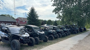 A row of ATVs parked along a sidewalk next to a building.