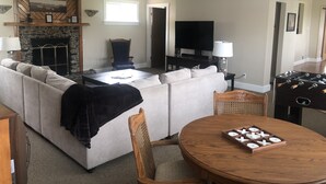 A living room with a sectional sofa, a wooden coffee table, a television, and a fireplace.