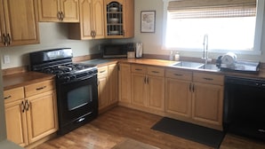 A kitchen with wooden cabinets, a stove, a microwave, and a sink.