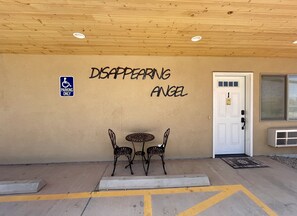 Guests enter through the entrance marked by the 'Disappearing Angel' sign, where a waiting area with two chairs is available.