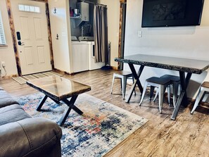 Cozy living space with a leather couch, dining table, and flat-screen TV.