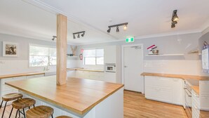 A modern kitchen with white cabinetry, wooden countertops, and a central island with stools.