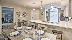 A dining area with a wooden table set for four, a kitchen with a marble island, and a view of the outdoors through a window. - 4 Mi to Strip: Cozy Lake-View Retreat in Branson (Branson)