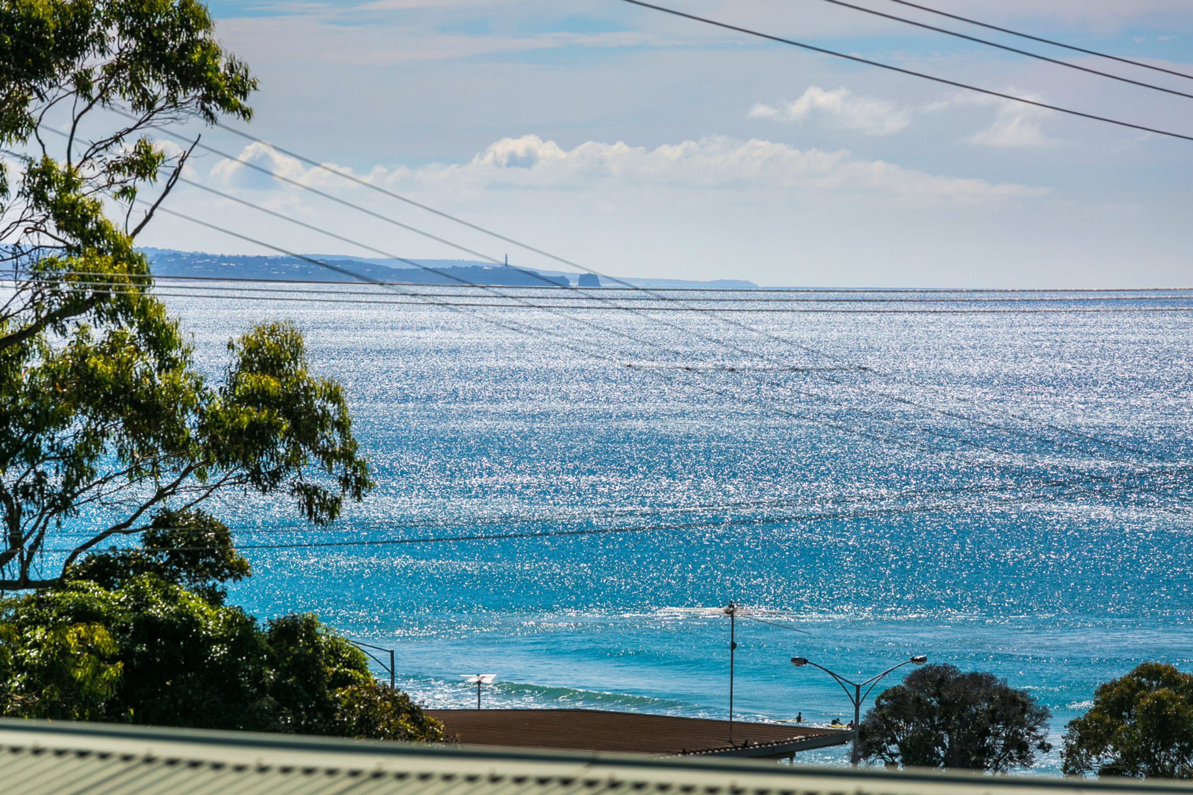 A coastal view with a clear sky, a body of water, and distant landforms.