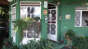 A green house with a large window, a clock, and various plants. - Two-story house - Furnas Lake - Guapé/MG (Neighboring Capitólio) (Guapé)