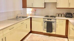 Eine moderne Küche mit weißen Schränken, einer Edelstahlspüle, einem Herd und einem Toaster.