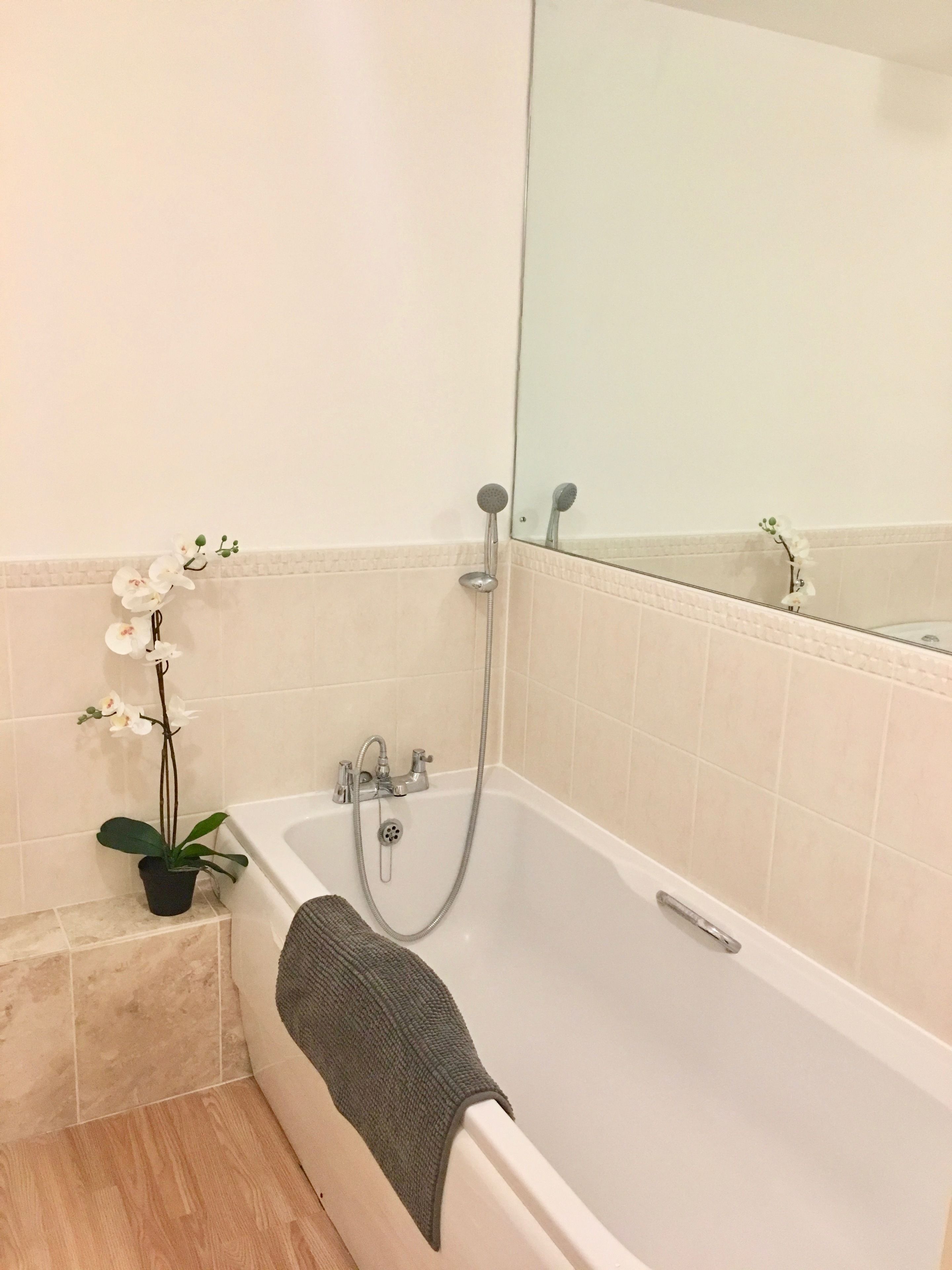 Un baño moderno con bañera, ducha y una pequeña orquídea en maceta.