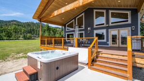 Una casa moderna con jacuzzi, terraza de madera y vistas a la montaña.