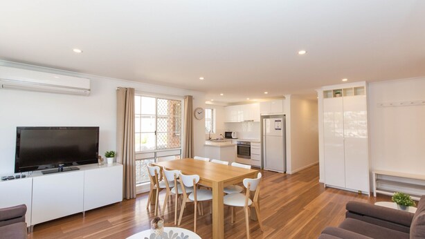 A modern apartment with a dining area, kitchen, living room, and a TV. - Oberlaken - 2/125 Gippsland Street (Jindabyne)