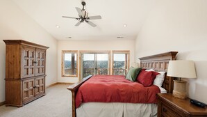 A bedroom with a large bed, wooden furniture, and a view through the windows. - Rock Canyon Ranch Lodge 2 Zion National Park (Orderville)