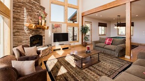 A spacious living room with a stone fireplace, a television, and a pool table. - Rock Canyon Ranch Lodge 2 Zion National Park (Orderville)