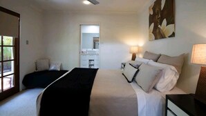 Un dormitorio con una cama, mesitas de noche, ventilador de techo, ventana y un cuadro en la pared.