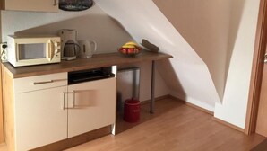 A compact kitchen with a microwave, coffee maker, and a fruit bowl on the counter. - Appartements Funk (Pfungstadt)
