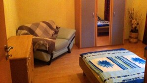 A bedroom with a bed, a wardrobe, a chair, and a suitcase. - Appartements Funk (Pfungstadt)