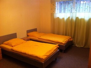 A room with two single beds, each with a wooden frame and a yellow blanket. - Appartements Funk (Pfungstadt)