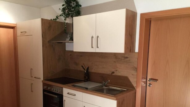 A kitchen with white cabinets, a wooden countertop, a double sink, and a built-in oven. - Appartements Funk (Pfungstadt)