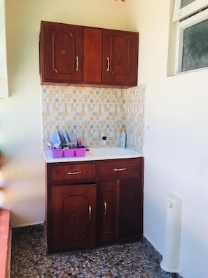 Compact kitchen area with a wooden cabinet structure, sink, and tiled backsplash.