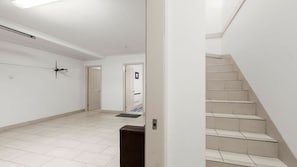 Un intérieur épuré et moderne, avec un escalier, des murs blancs et un sol carrelé.