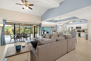 A spacious living area with a large sofa, a dining table, and a kitchen in the background.