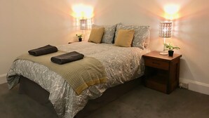 A bedroom with a large bed, two bedside lamps, a nightstand, and a small potted plant. - Highfield University House (Southampton)