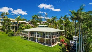 A modern resort with a glass-roofed building surrounded by lush greenery and palm trees. - Cape Breeze - 5 BR home with headland views (Byron Bay)
