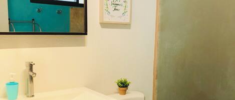 A bathroom with a white sink, a mirror, a toilet, and a shower enclosure.