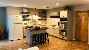 A modern kitchen with a central island, stainless steel appliances, and wooden flooring.