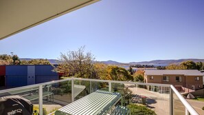 A balcony with a view of a lake, mountains, and buildings. - Silvermist - 17 Poley Cow Lane (Jindabyne)