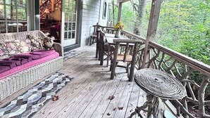 A wooden deck with a sofa and a table, surrounded by a railing. - Hidden Hollow 2 BR 2 baths WALK to town (Highlands)