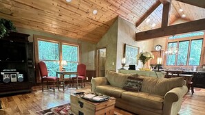 A spacious living room with wooden floors, a large sofa, a coffee table, and a red chair. - Hidden Hollow 2 BR 2 baths WALK to town (Highlands)