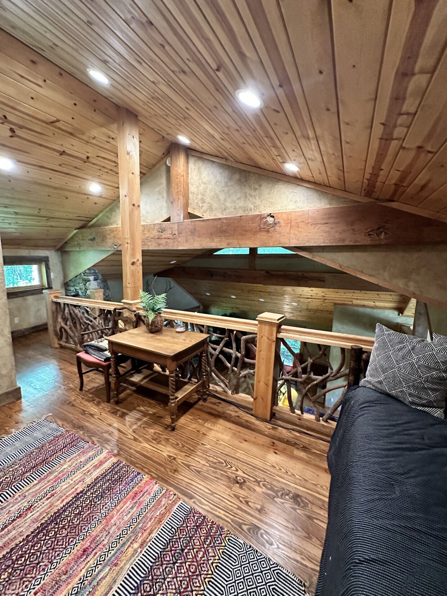 Interior acogedor de una cabaña con una mesa de comedor de madera, un sofá y una chimenea de piedra.
