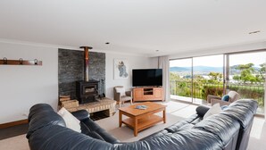 Een moderne woonkamer met een stenen openhaard, een flatscreen televisie en een bank die uitkijkt op een balkon met een prachtig uitzicht.