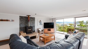Een moderne woonkamer met een stenen openhaard, een flatscreen televisie en een bank die uitkijkt op een balkon met een prachtig uitzicht.