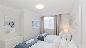 Ein Hotelzimmer mit zwei Betten, einem Schminktisch, einem Spiegel und Bildern an den Wänden.