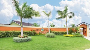 Un espace paysager agrémenté d’un panneau indiquant « Drax Hall Manor » et de palmiers.