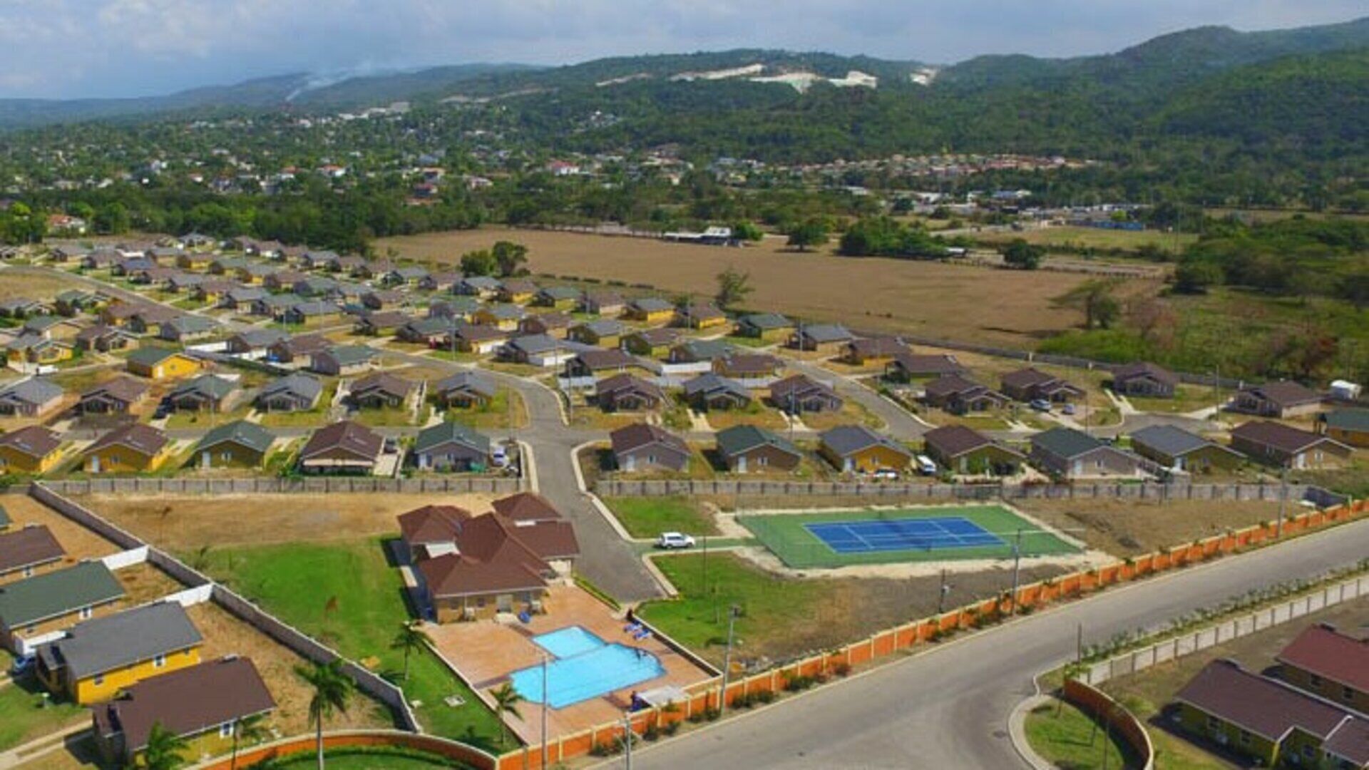 Un quartier résidentiel avec des maisons, une route et un court de tennis.