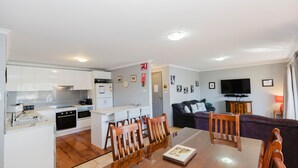 Eine moderne Wohnung mit Küche, Essbereich, Wohnzimmer und Fernseher.