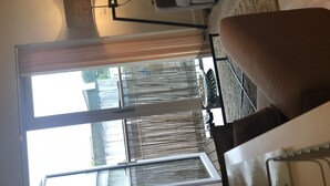 Ein Wohnzimmer mit einer Couch, einem Couchtisch und einem Fenster mit Jalousien.