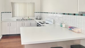Une cuisine moderne avec des meubles blancs, une cuisinière et un évier.