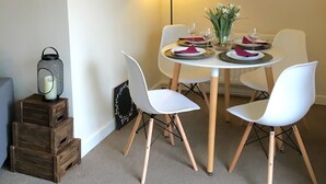 A dining area with a round table, white chairs, and a red floor lamp.