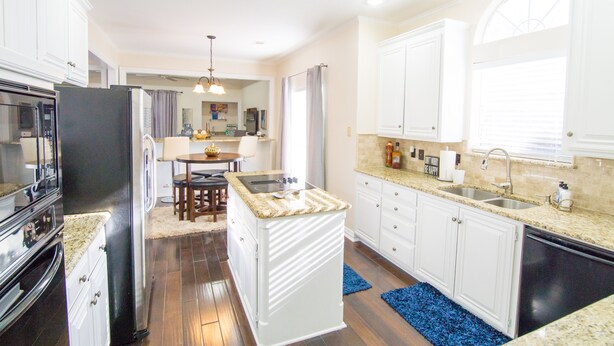 Eine moderne Küche mit weißen Schränken, einer Granitabdeckung und einem Essbereich mit Tisch und Stühlen.