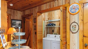 A laundry area with a washing machine, drying rack, and a metal tiered tray. - ROCKY TOP LOG CABIN-PET FRIENDLY (MAGGIE VALLEY)