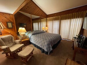 A cozy room with a large bed, two bedside lamps, a wooden chair, a small table, and a television. - 5 bedroom/4 bath TH, with private boat dock on Lake Travis in Point Venture (Point Venture)