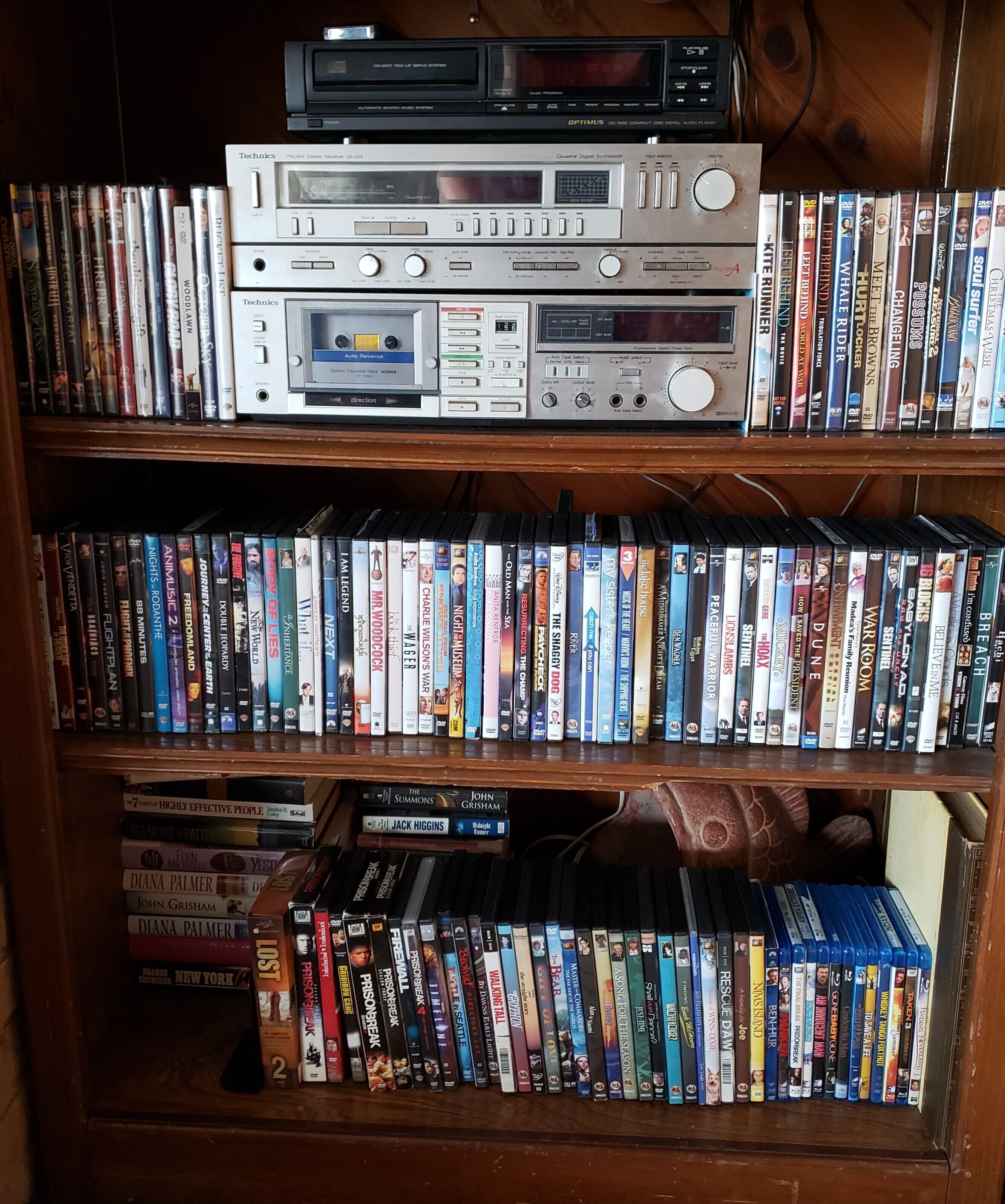 A bookshelf filled with DVDs and a stack of audio equipment.