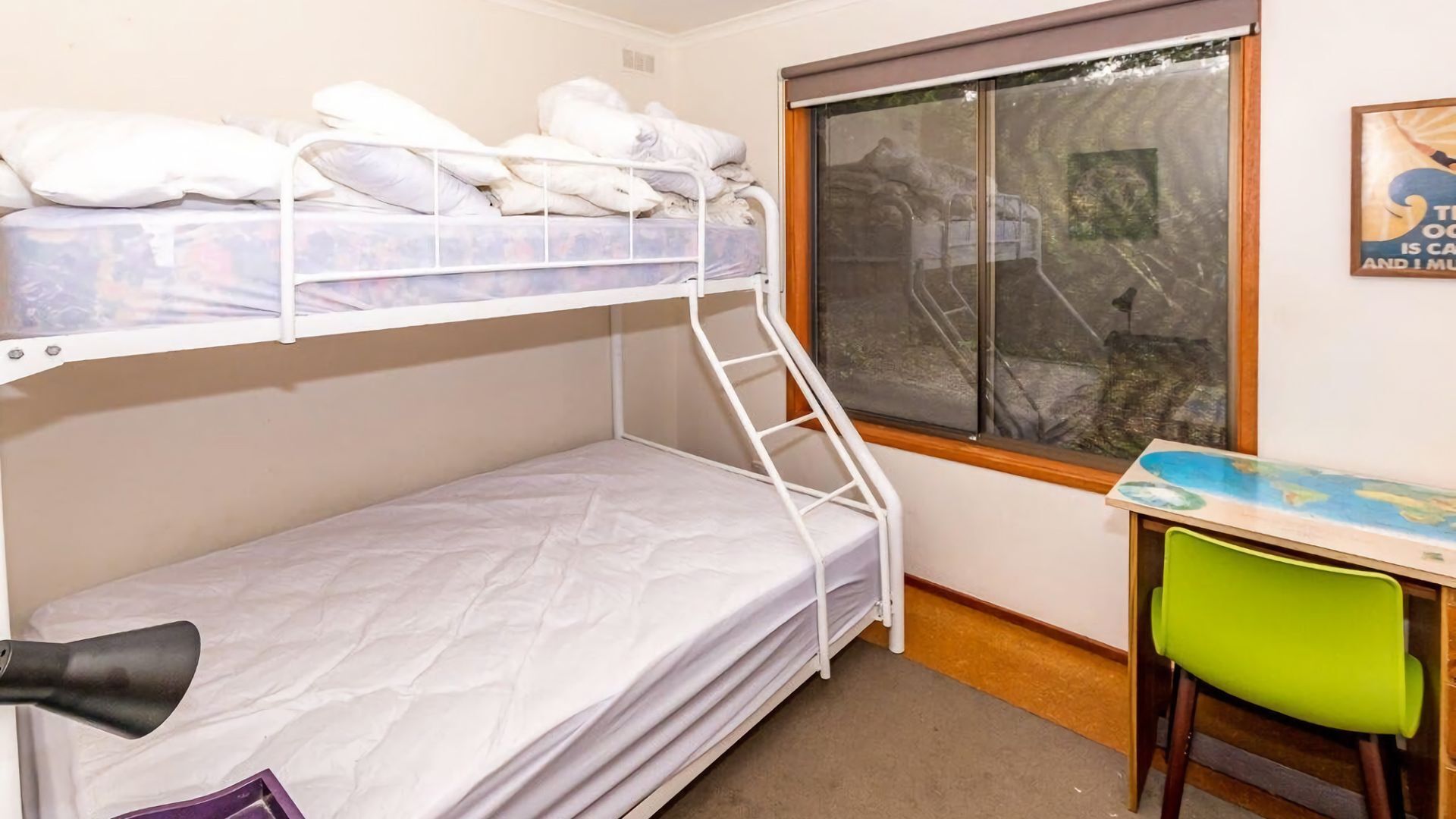 A bunk bed room with a window, a desk, and a chair.