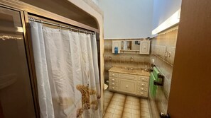 Un baño con cortina de ducha, lavamanos y espejo.