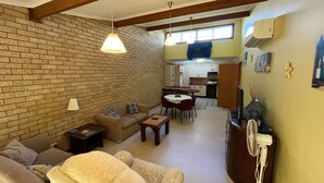 Un salon avec un mur en briques, un canapé, une table et un ventilateur.