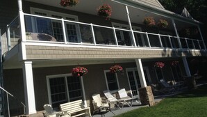 A two-story house with a balcony, outdoor seating area, and hanging flower baskets. - Beautiful family retreat (Wayne)